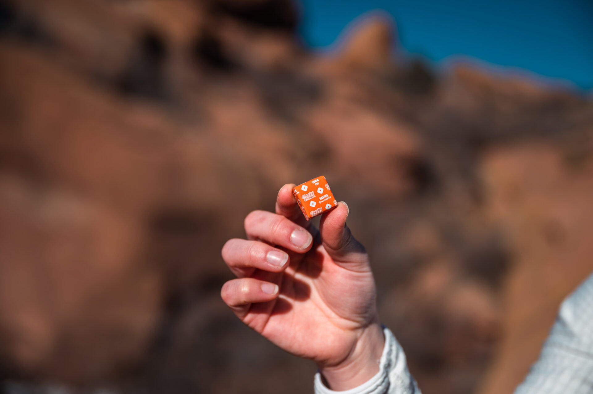 Hand holding a Cheeba Chews Sativa Chocolate chew against Colorado red rocks
